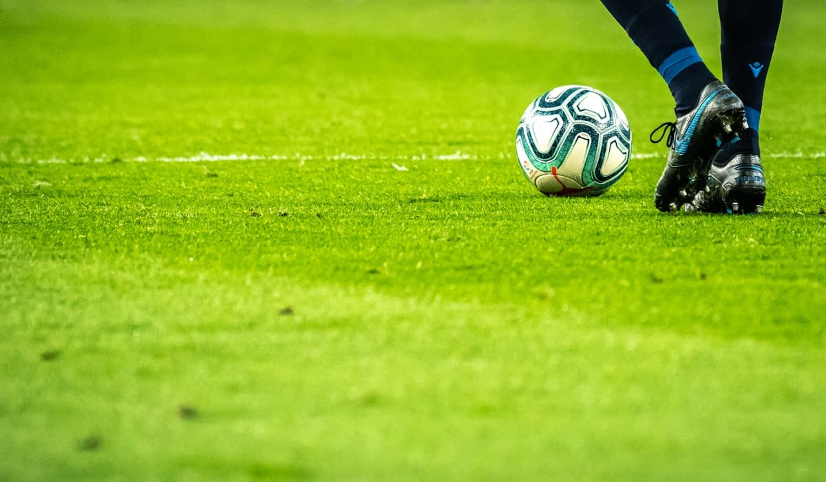 Fotballspiller med ball på kunstgress — illustrasjonsfoto.